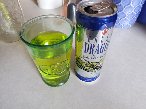 A picture of Green Dragon Energy drink in a can next to some of it poured in a glass