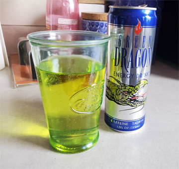 A can of Green Dragon energy drink next to a glass of it. It's green and looks radioactive